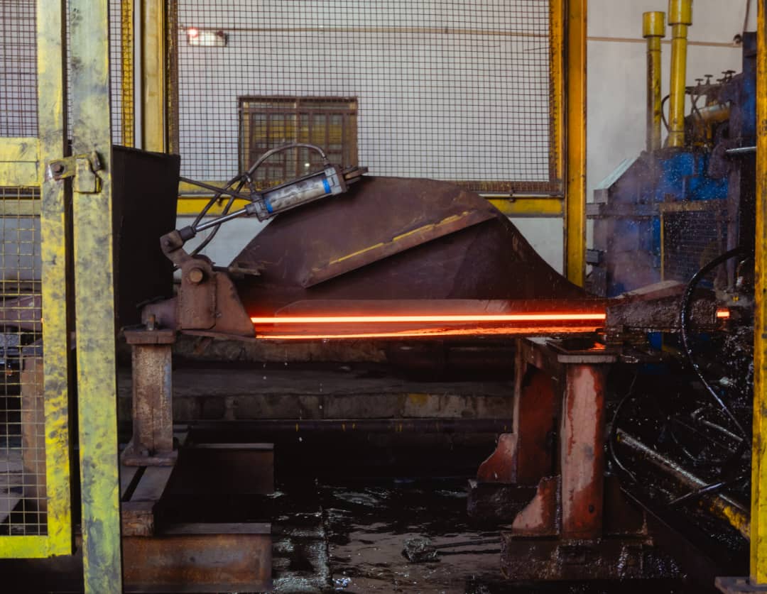Glowing hot steel bar moving through the rolling mill